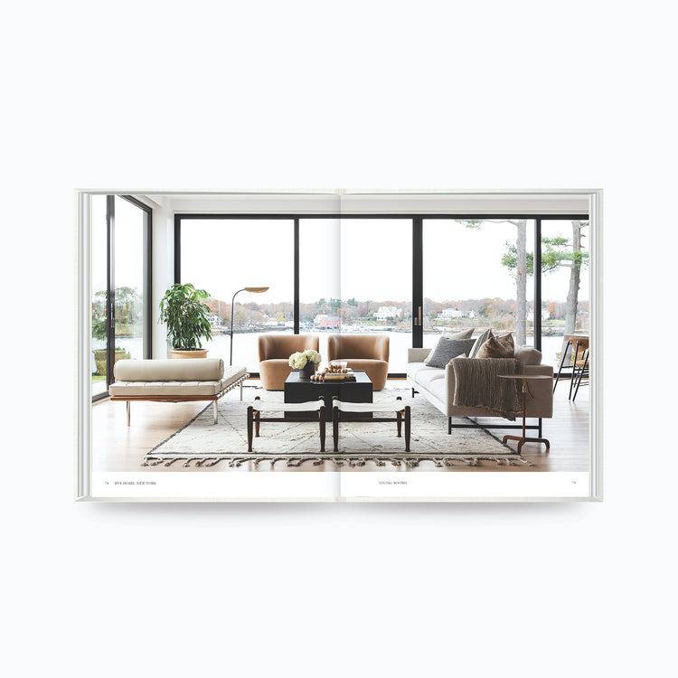 Open book showing modern living room design with large windows and neutral furniture from The Art of Home by Shea McGee