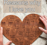 Heart-shaped wooden puzzle with engraved love messages, held by two hands on a neutral surface