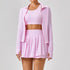 Woman in light pink pleated tennis skirt, crop top, and zip-up jacket set, sporty fit