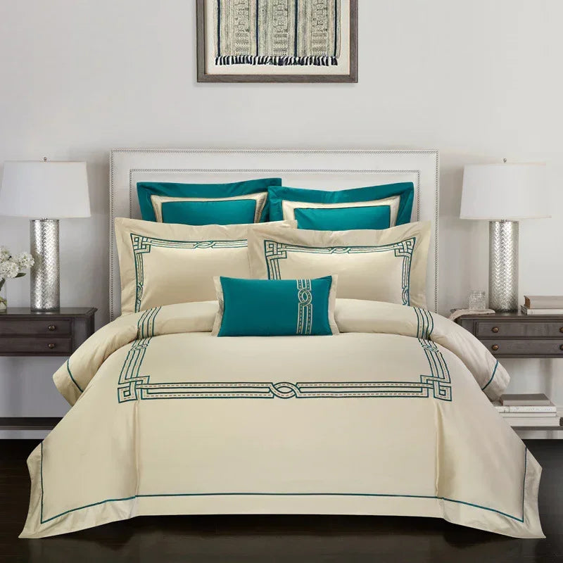 Elegant cream bedding set with teal geometric trim and matching decorative pillows on a modern bed.