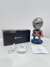 Silver and red robot toy with helmet, remote control, user manual, and box on white table