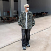 Person in oversized camouflage jacket, loose white T-shirt, distressed black jeans, and sneakers