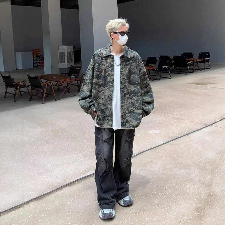 Person in oversized camouflage jacket, loose white T-shirt, distressed black jeans, and sneakers
