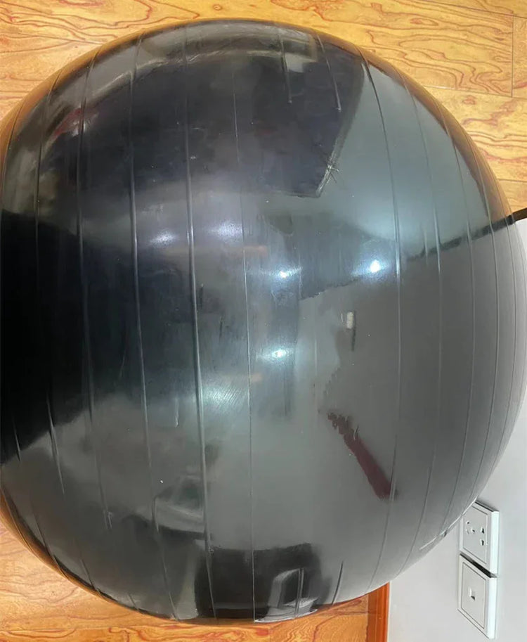 Black exercise stability ball with glossy finish on a wooden floor