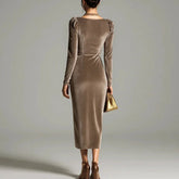 Woman wearing a fitted taupe velvet long sleeve midi dress with puff shoulders
