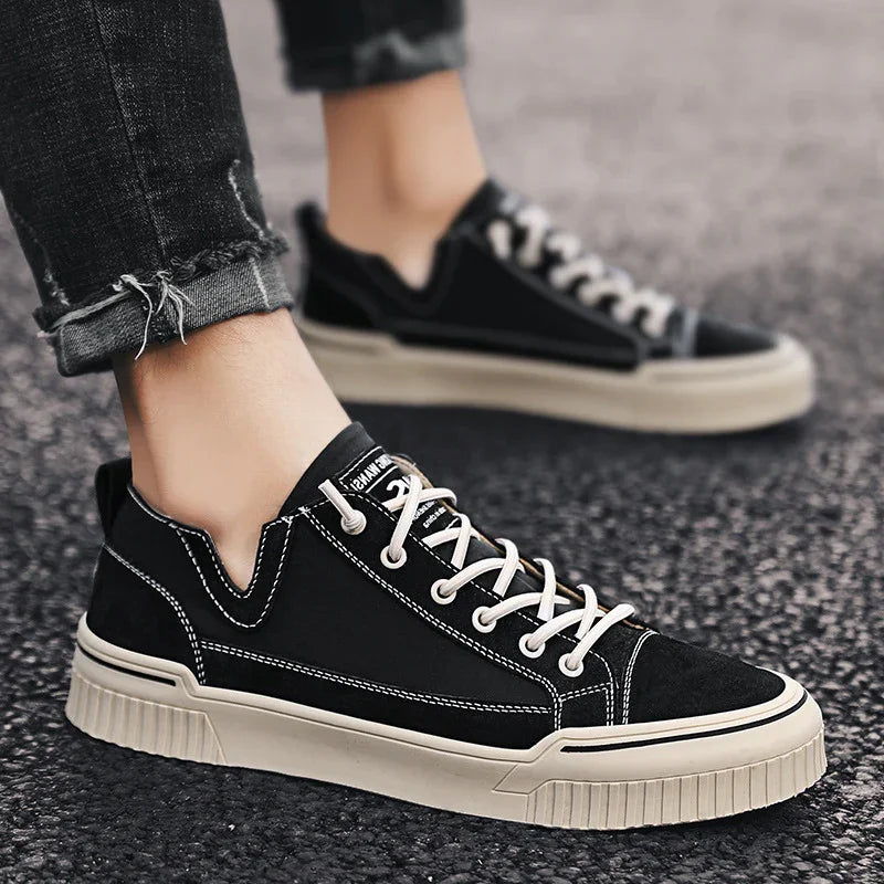 Black low-top sneakers with white stitching and beige sole, casual streetwear style