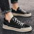 Black low-top sneakers with white stitching and beige sole, casual streetwear style