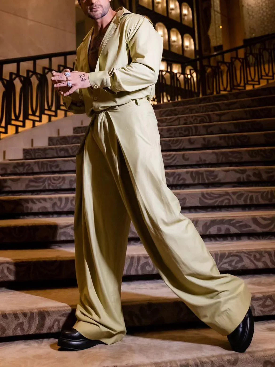 Man wearing light khaki oversized wide-leg pants and matching loose shirt on staircase