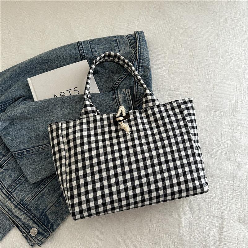 Black and white gingham tote bag with rope closure on denim jacket, casual streetwear style