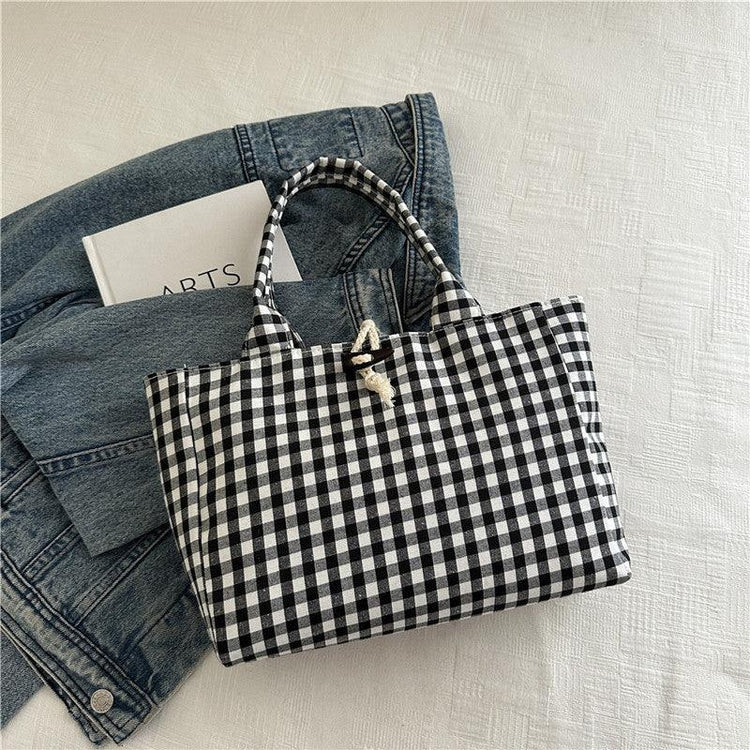 Black and white gingham tote bag with rope closure on denim jacket, casual streetwear style