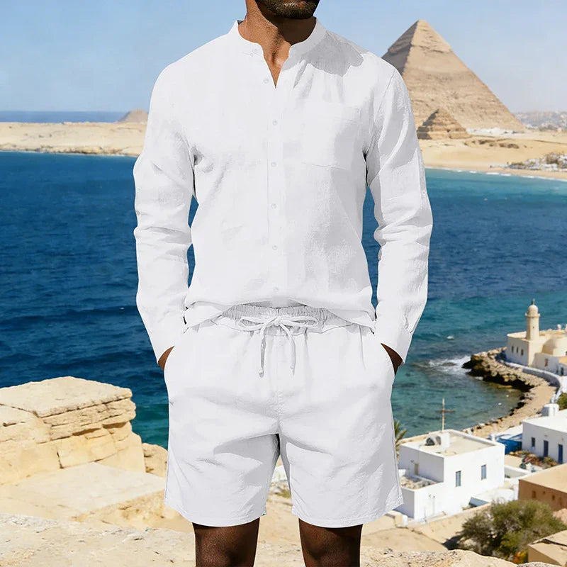Man wearing a white linen long-sleeve shirt and drawstring shorts, relaxed fit, coastal background