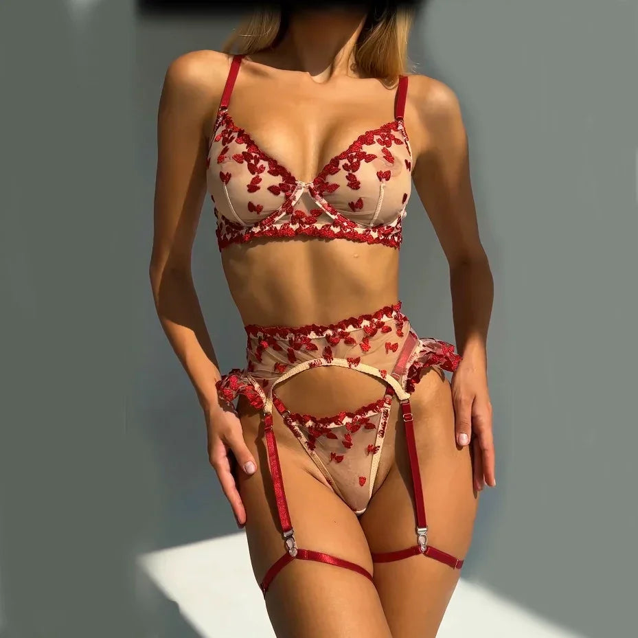 Sheer nude mesh lingerie set with red embroidered floral details, underwire bra, garter belt, and matching thong, fitted style