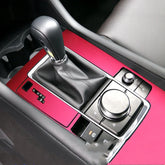 Modern car interior with black leather gear shift and glossy red center console trim