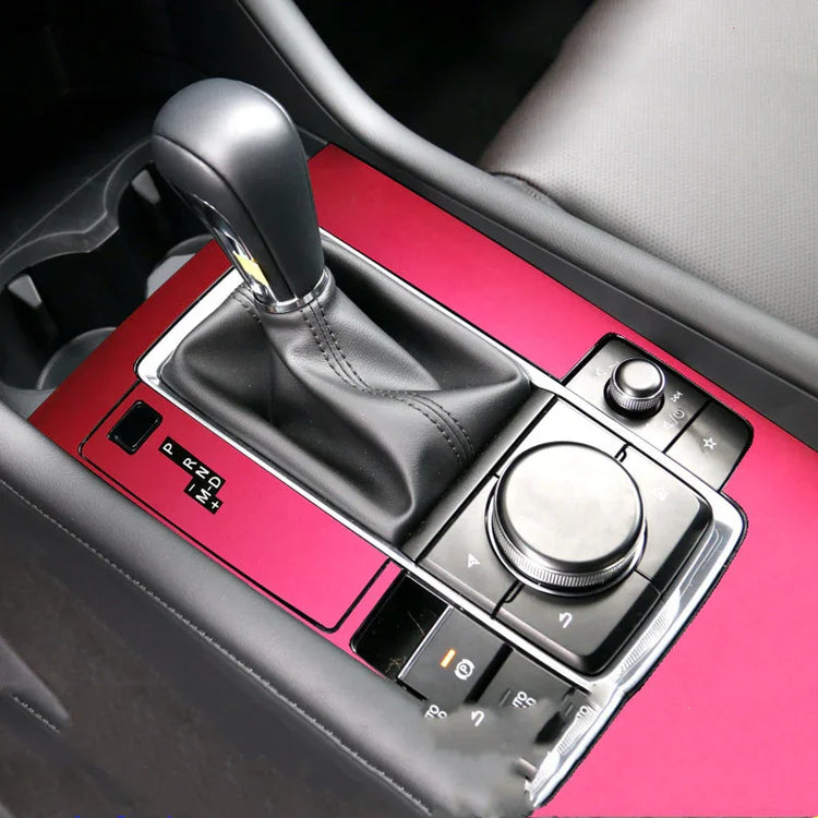 Modern car interior with black leather gear shift and glossy red center console trim