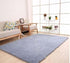 Modern living room with a light blue shag rug, beige sofa, and wood flooring