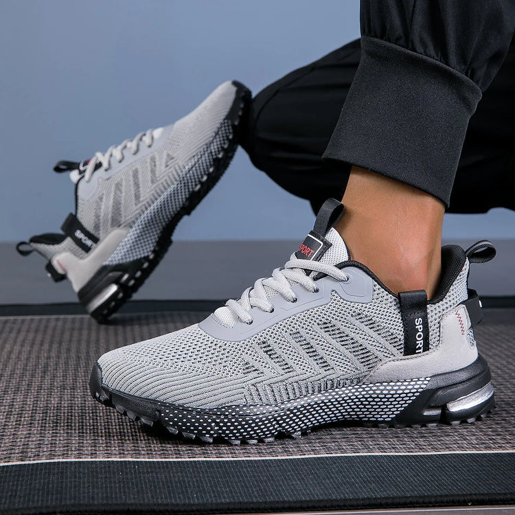 Light gray knit mesh sneakers with black soles, slip-on fit, and modern streetwear style
