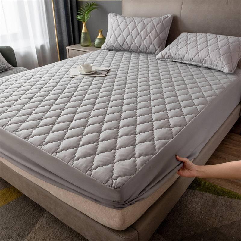 Gray quilted mattress cover with diamond stitching, soft material, fitted design, modern bedroom