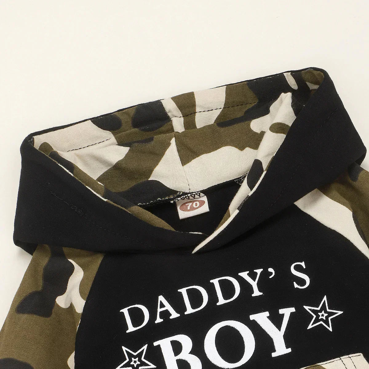 Closeup of a camo and black cotton hoodie with white graphic text and relaxed fit