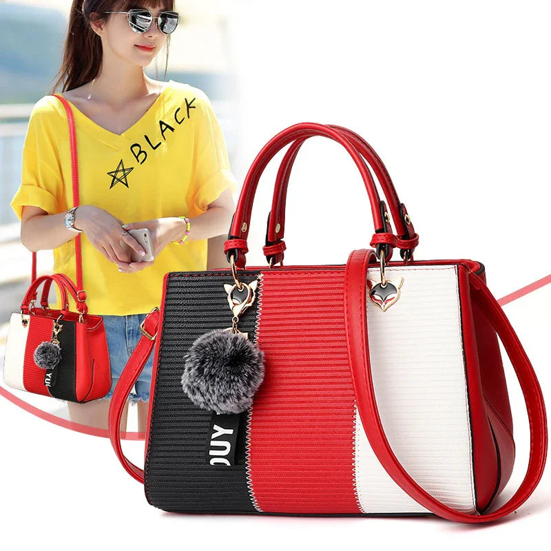 Colorblock crossbody handbag with red, black, and white panels, textured material, structured fit, faux fur keychain, and gold hardware.
