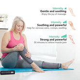 Woman wearing grey leg compression sleeves, pink sleeveless top, and grey leggings, seated on a mat in a bright room.