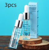 Clear glass serum bottles with silver caps and dropper tops, displayed on wooden rounds