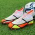 High-top soccer cleats with white, orange, and yellow mesh upper on green field