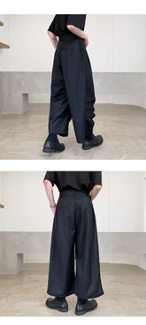Wide-leg black pants with a relaxed fit, high waist, and smooth fabric, styled with black shoes.