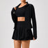 Woman wearing black athletic crop top, zip-up jacket, and pleated skirt, fitted activewear