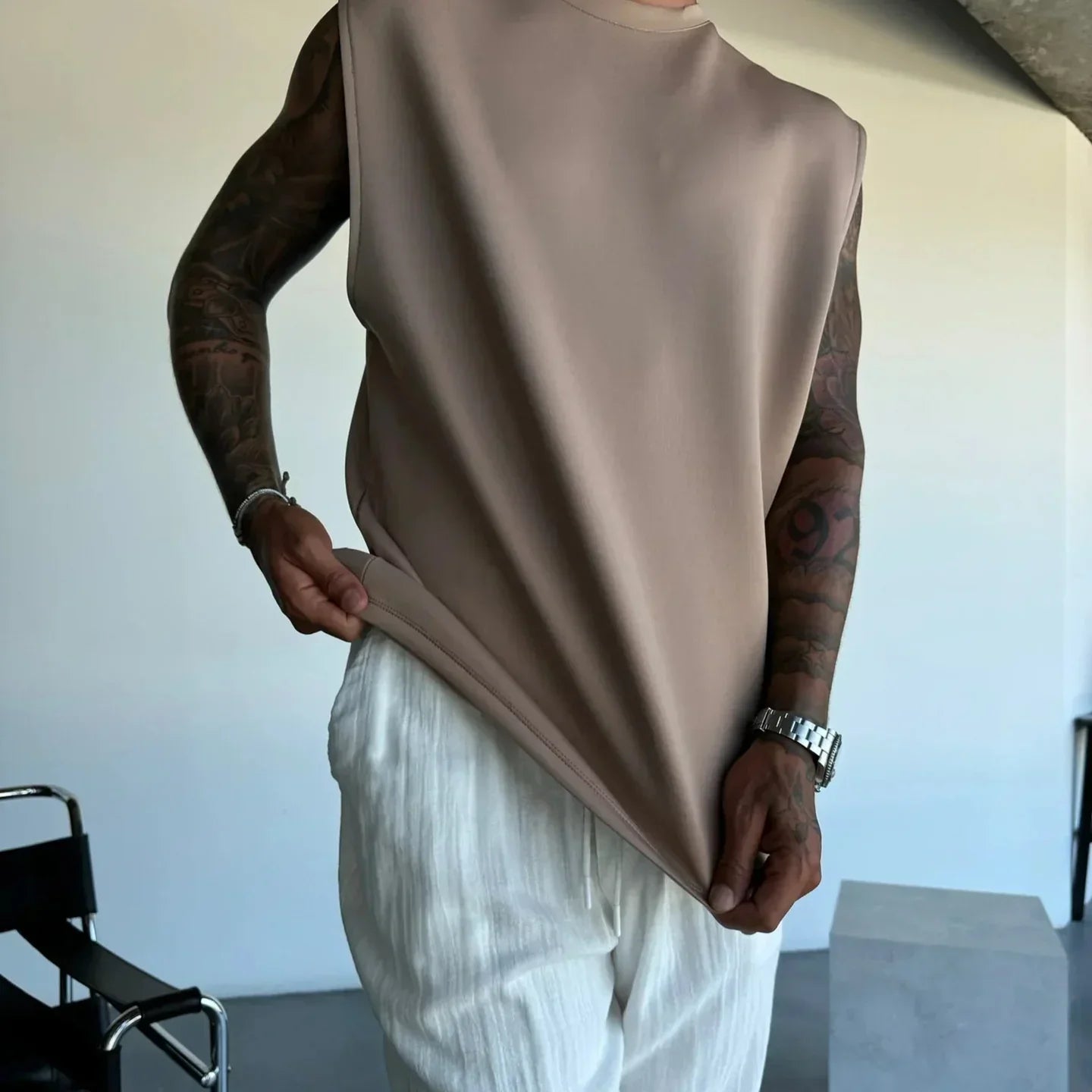 Sleeveless beige oversized top with a relaxed fit, paired with white textured pants