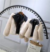 Beige faux fur jackets with black leather collars, cropped fit, hanging on a rack