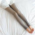 Sheer gray tights with a smooth finish, slim fit, styled with white shirt on bed