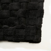 Black plush fleece fabric with quilted texture, showcasing soft and cozy material.
