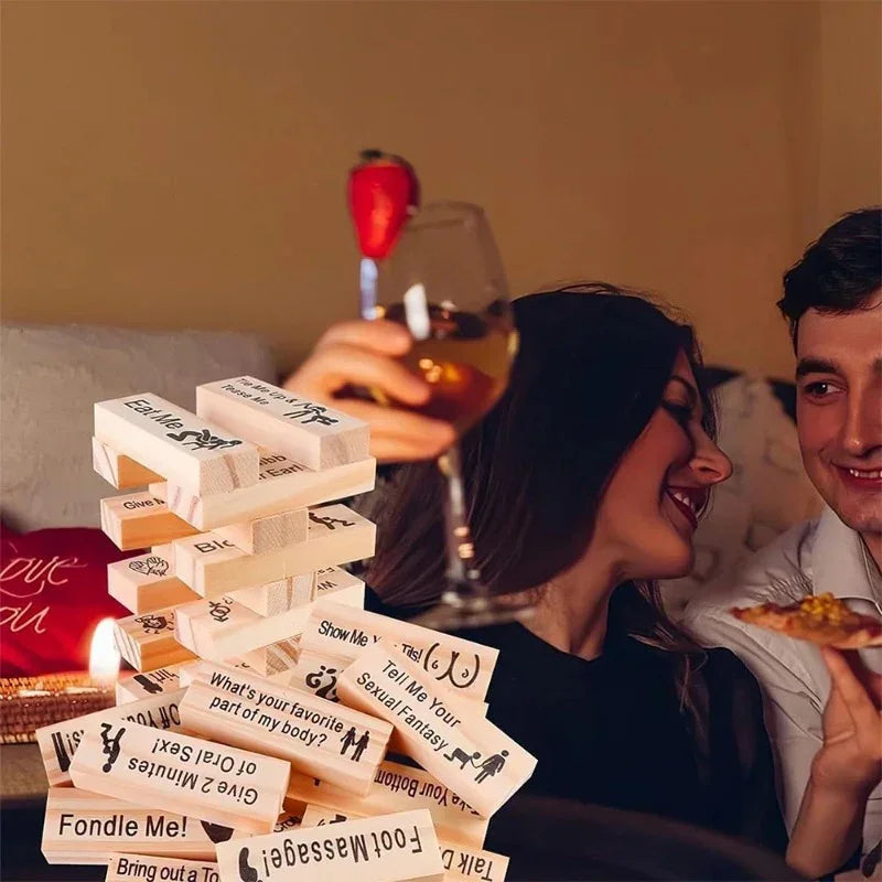 Couple in cozy setting playing a wooden block party game with playful text on pieces.