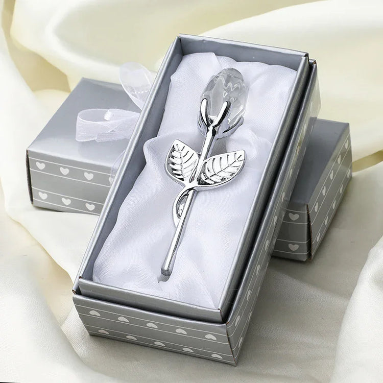 Silver metal rose with crystal bud in a gray heart-patterned gift box on white satin