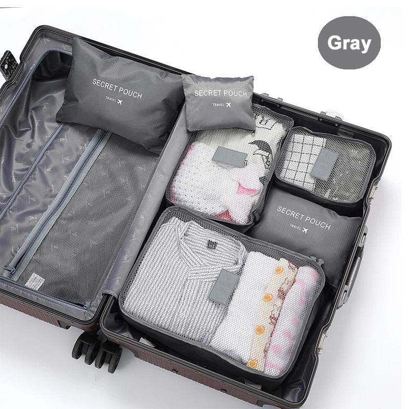 Gray mesh travel packing cubes with neatly folded clothes inside an open suitcase.