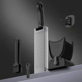 Modern kitchen utensil set with black and silver slicer, brushes, and holder on gray background
