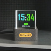 Modern transparent digital clock with colorful LED display and black rectangular base