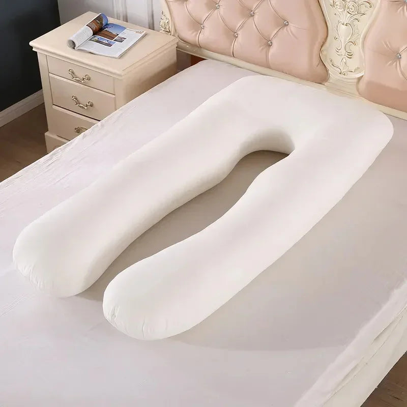 U-shaped white body pillow with soft fabric on a bed in a modern bedroom setting