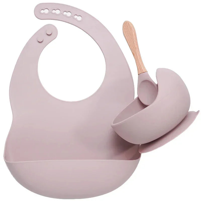 Dusty pink silicone baby bib, bowl, and spoon set with wooden handle, soft material