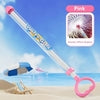 Pink water gun with clear barrel and heart-shaped handle, beach scene, nozzle spray effect shown