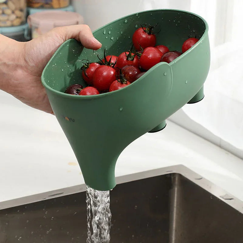 Green plastic colander rinsing cherry tomatoes over a kitchen sink.