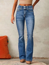 Woman wearing high-waisted blue denim flared jeans with a slim fit and double button closure.