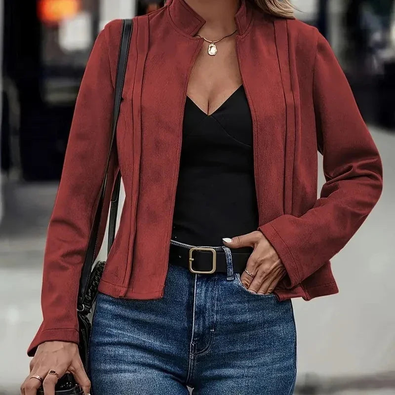 Woman wearing a fitted maroon suede jacket, black top, and high-waisted blue jeans.
