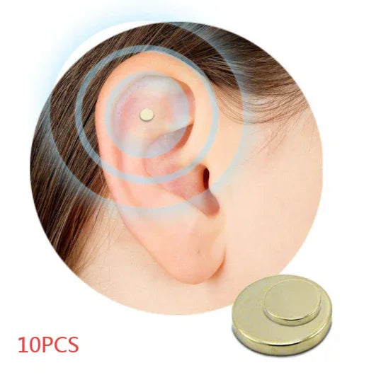 Close-up of a small gold magnetic ear acupressure stud on ear cartilage, minimalist design.