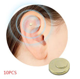 Close-up of a small gold magnetic ear acupressure stud on ear cartilage, minimalist design.
