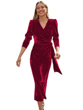 Woman wearing a red velvet wrap midi dress with long sleeves and a fitted waist