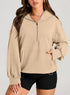 Woman wearing a beige oversized quarter-zip hoodie with kangaroo pocket and black fitted shorts