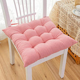 Soft pink tufted cotton seat cushion on a white wooden chair in a cozy room