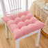 Soft pink tufted cotton seat cushion on a white wooden chair in a cozy room