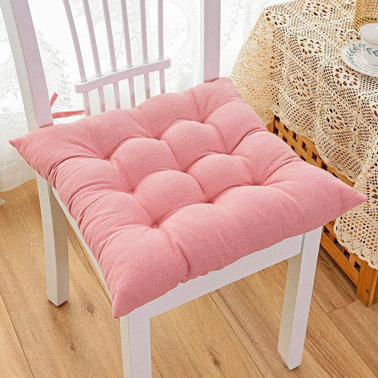 Soft pink tufted cotton seat cushion on a white wooden chair in a cozy room